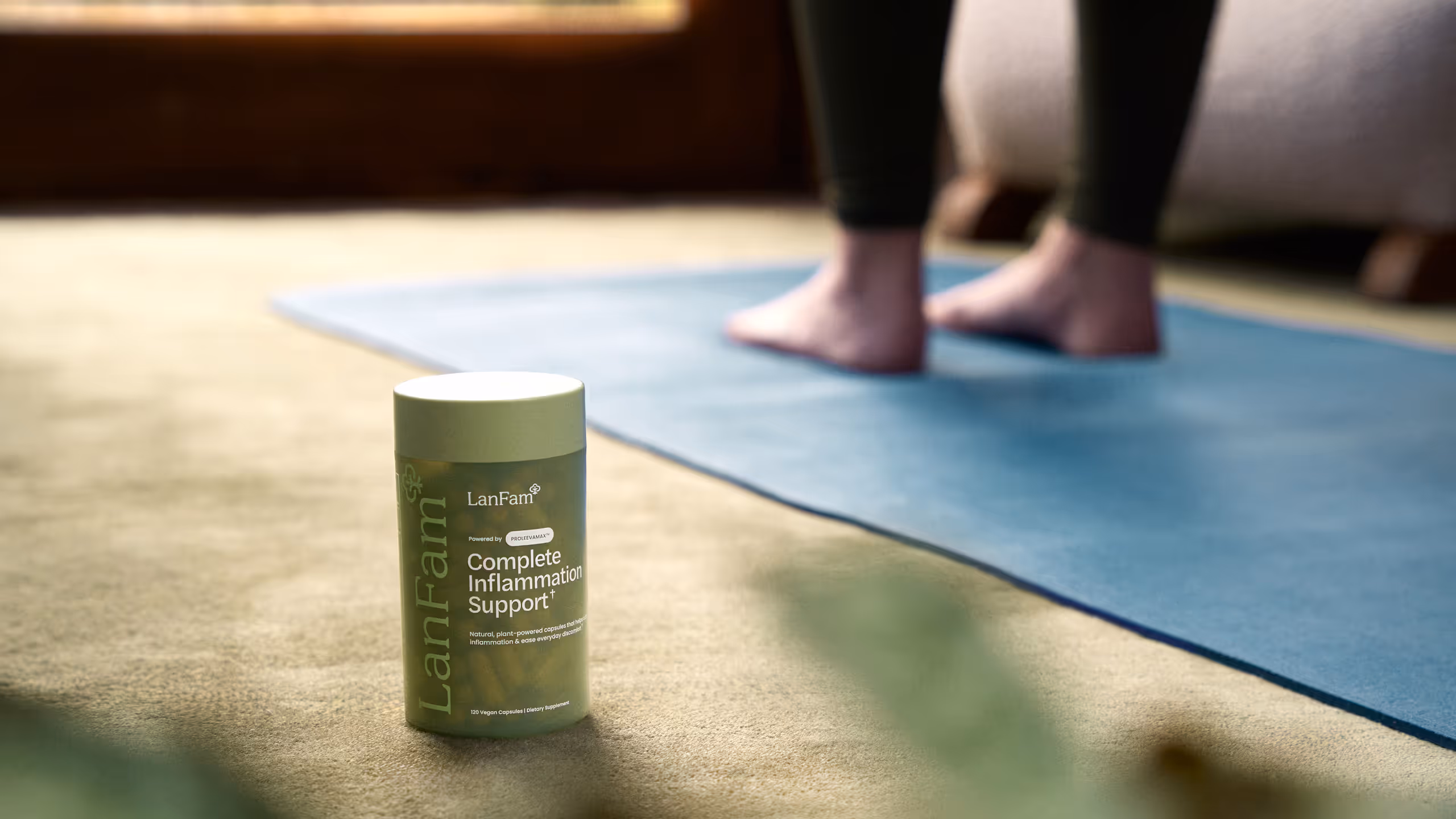 A ProleevaMax jar on a carpet at the edge of a blue yoga mat with bare feet behind